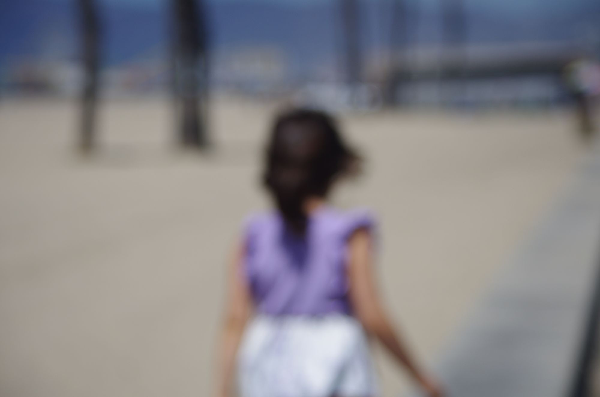 A girl in purple walking on the boardwalk, out of focus