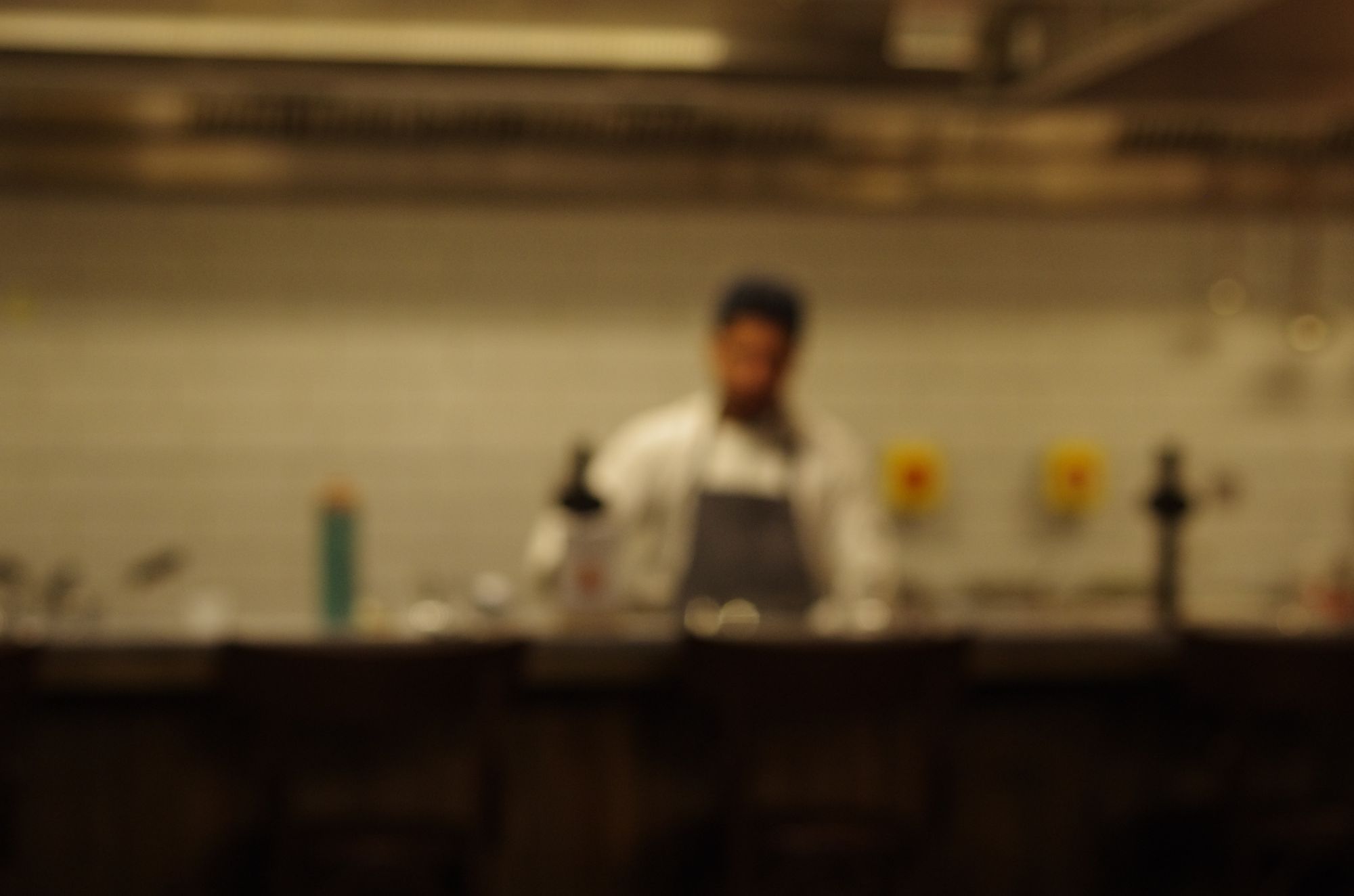 A cook behind a warm-lit counter, out of focus