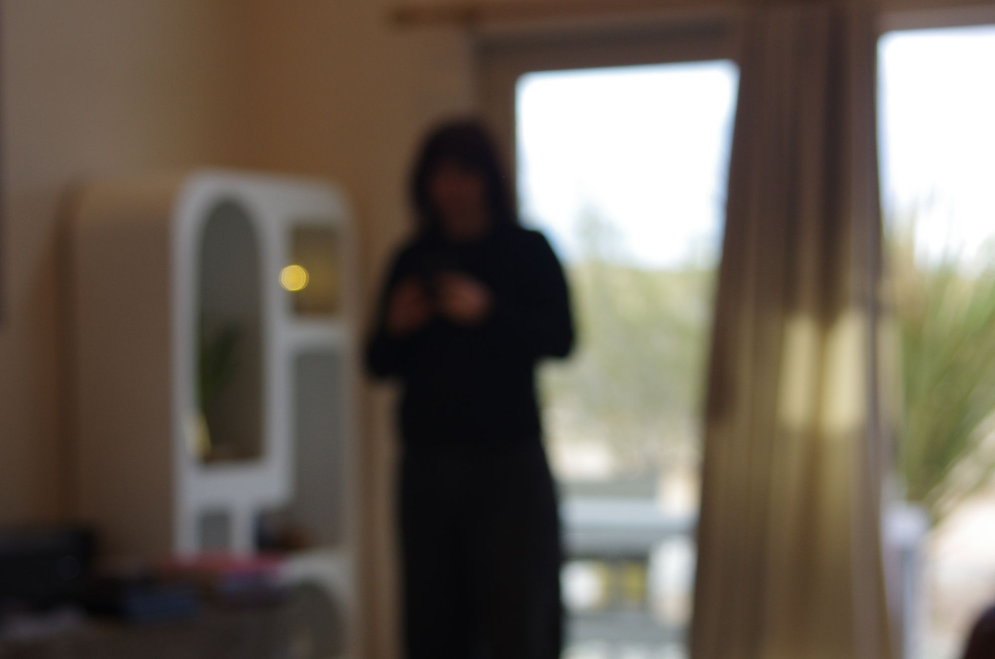 A silhouette standing by a bright window, out of focus